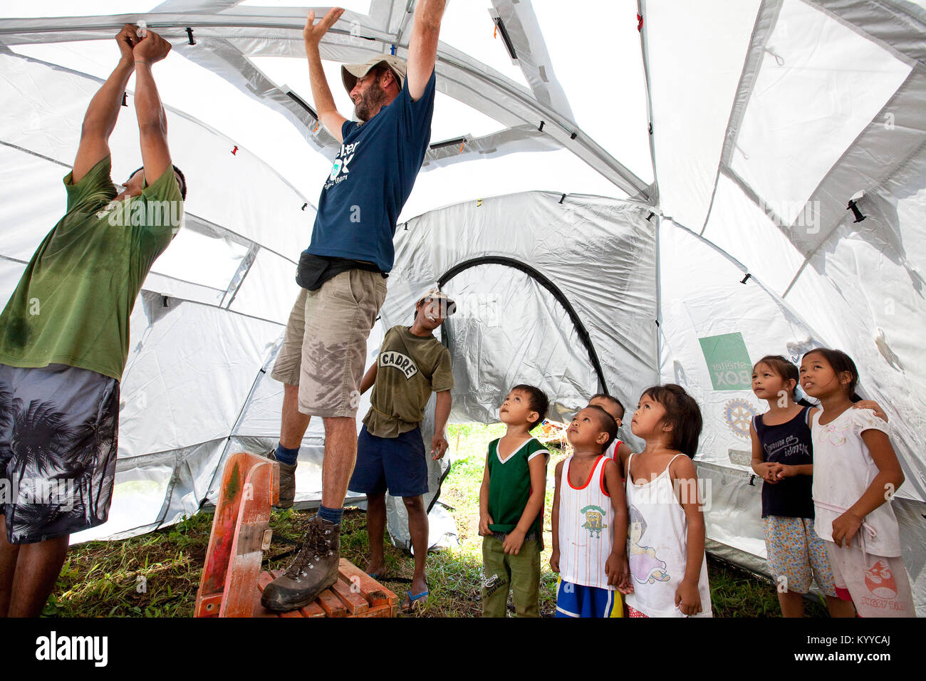 Elemento di SRT, Harry Roberts (UK) viene illustrato come impostare un rilievo tenda con volontari rotariani e beneficiari locali. Balinad, Albay, Filippine Foto Stock