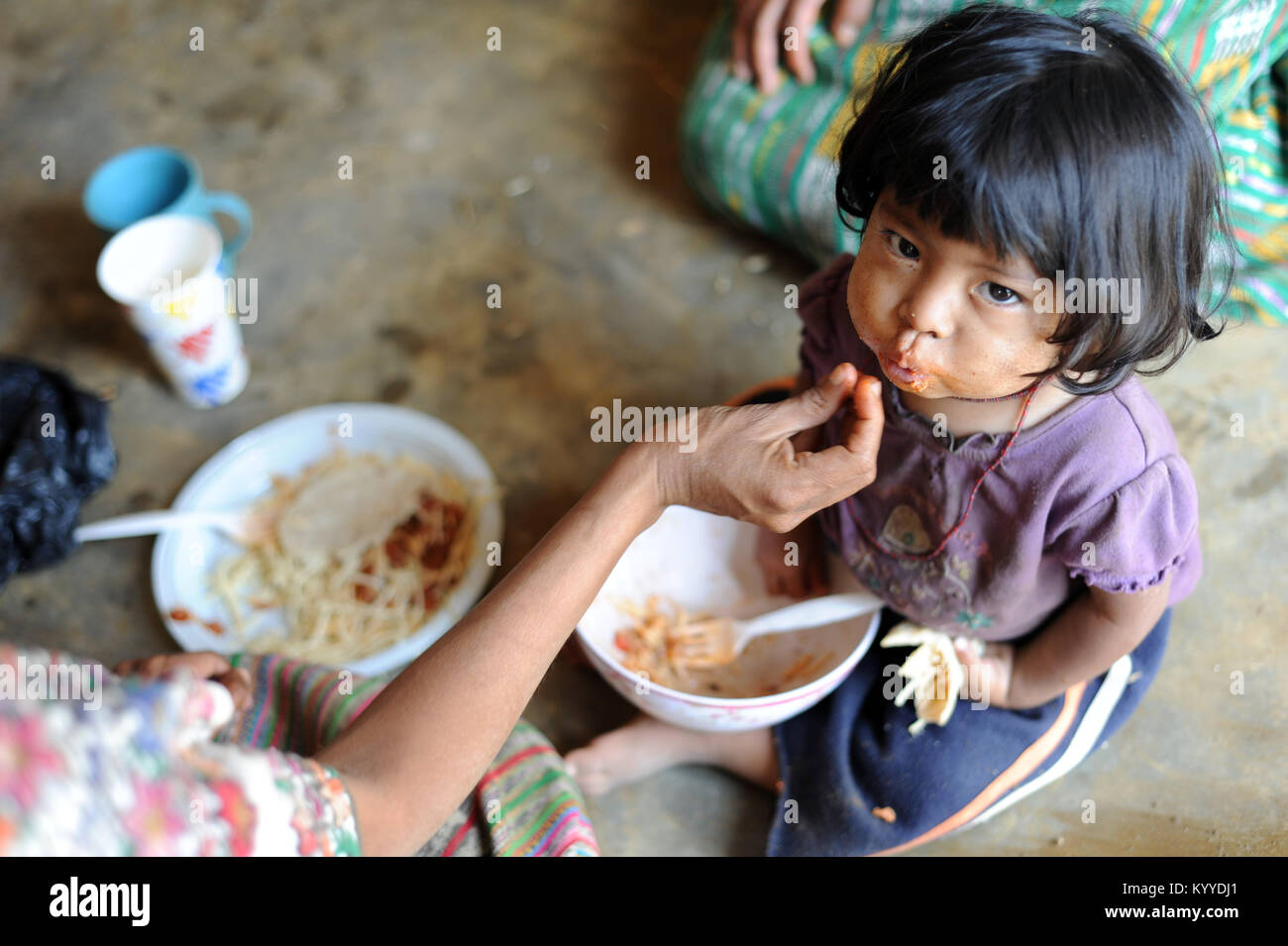 Un maya ragazza indigena è alimentato pasto fornite dagli enti locali NPO in Aqua Escondida, Solola, Guatemala. Foto Stock