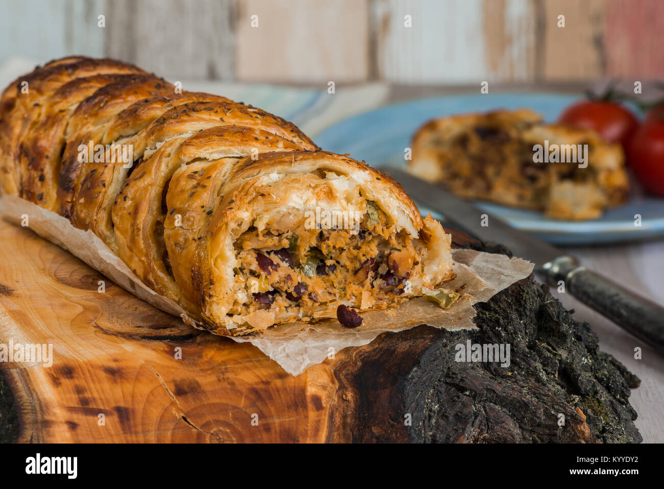 Rotolo di maiale - salsiccia piccante di carne con peperoncino e fagioli in pasta sfoglia sul tavolo di legno Foto Stock