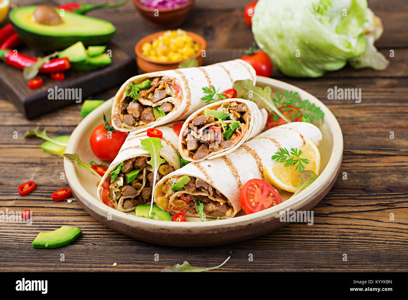 Burrito si avvolge con manzo e verdure su un sfondo di legno. Carni bovine burrito , cibo messicano. Cibo sano e background. Cucina messicana. Foto Stock