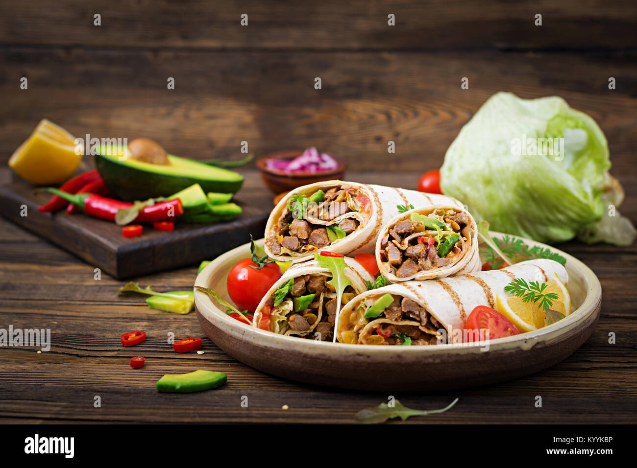 Burrito si avvolge con manzo e verdure su un sfondo di legno. Carni bovine burrito , cibo messicano. Cibo sano e background. Cucina messicana. Foto Stock
