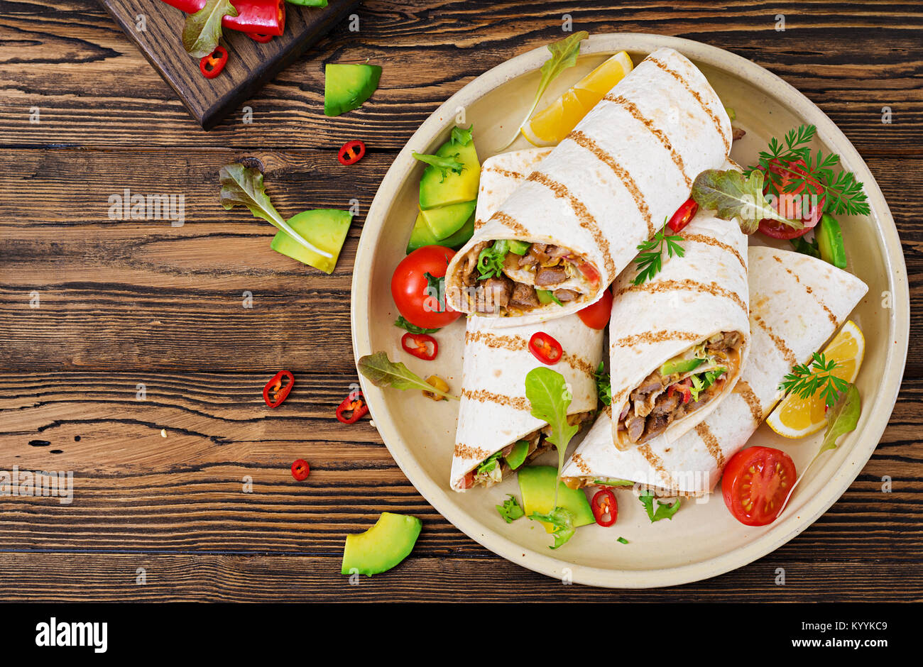 Burrito si avvolge con manzo e verdure su un sfondo di legno. Carni bovine burrito , cibo messicano. Cibo sano e background. Cucina messicana.Vista dall'alto. Foto Stock