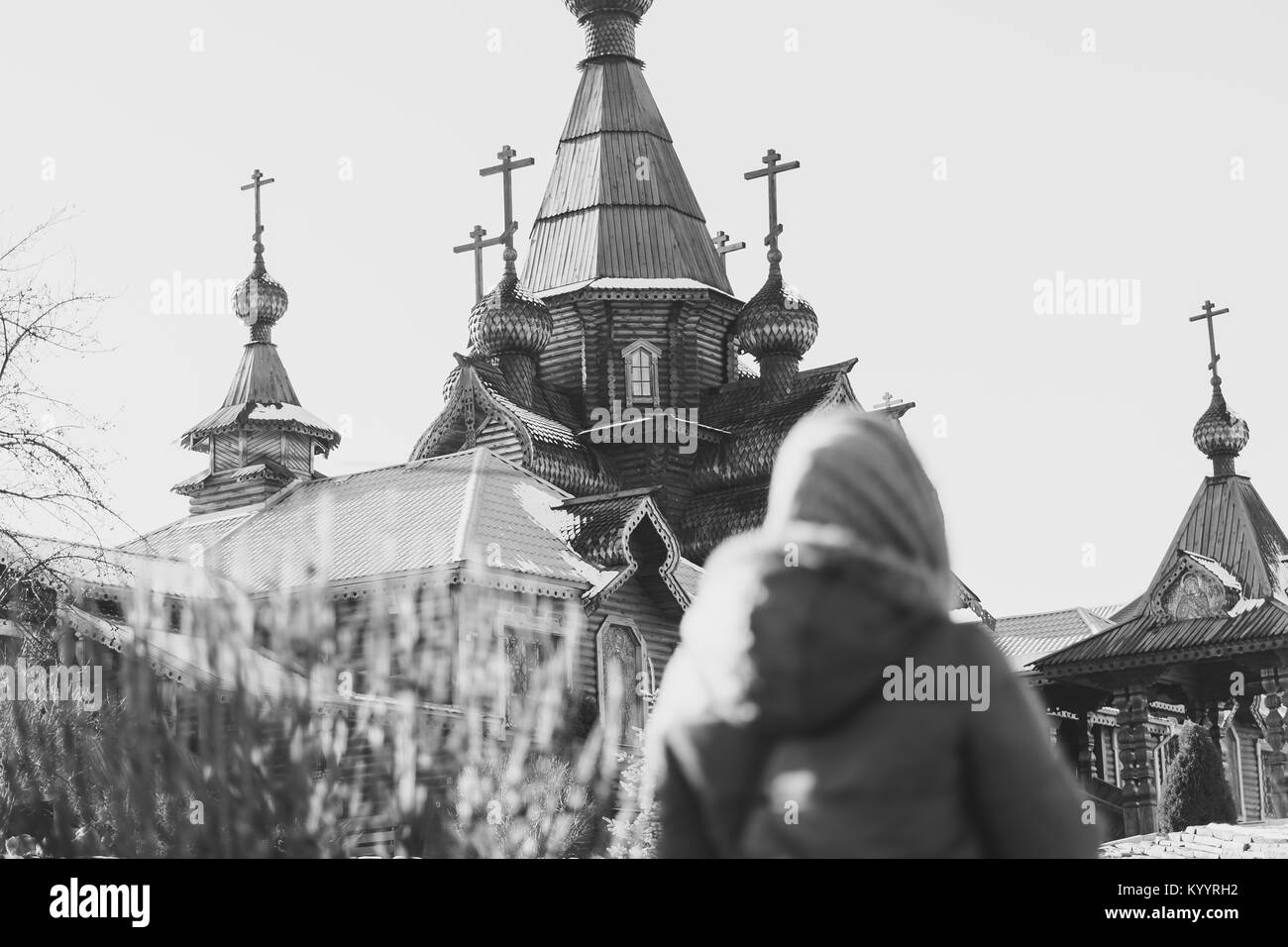 Una donna guarda ad una chiesa in legno in Russia Foto Stock