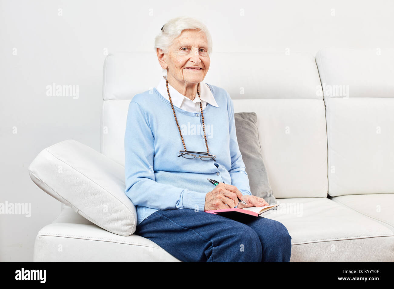 Felice vecchia donna è seduta sul divano di casa o in una casa di riposo Foto Stock