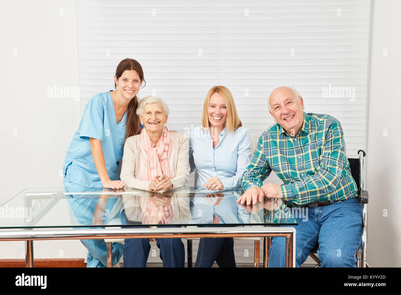 Il caregiver e la famiglia felice con i genitori e la figlia in una casa di riposo Foto Stock