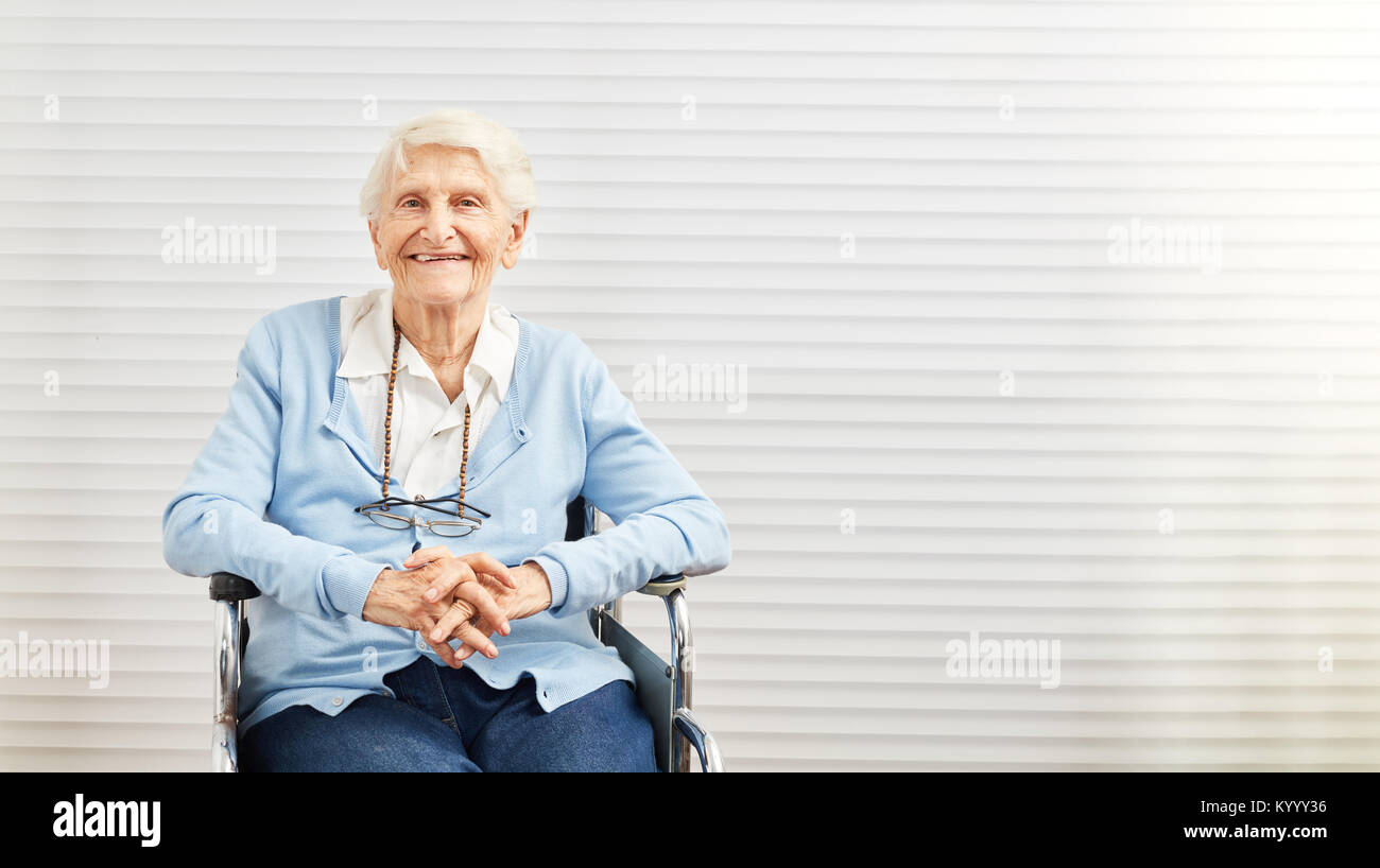 Sorridente vecchia donna seduta in sedia a rotelle in casa di riposo o senior citizen residence Foto Stock