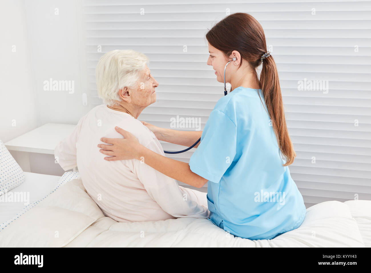 Infermiera con uno stetoscopio sta esaminando un malato donna anziana Foto Stock