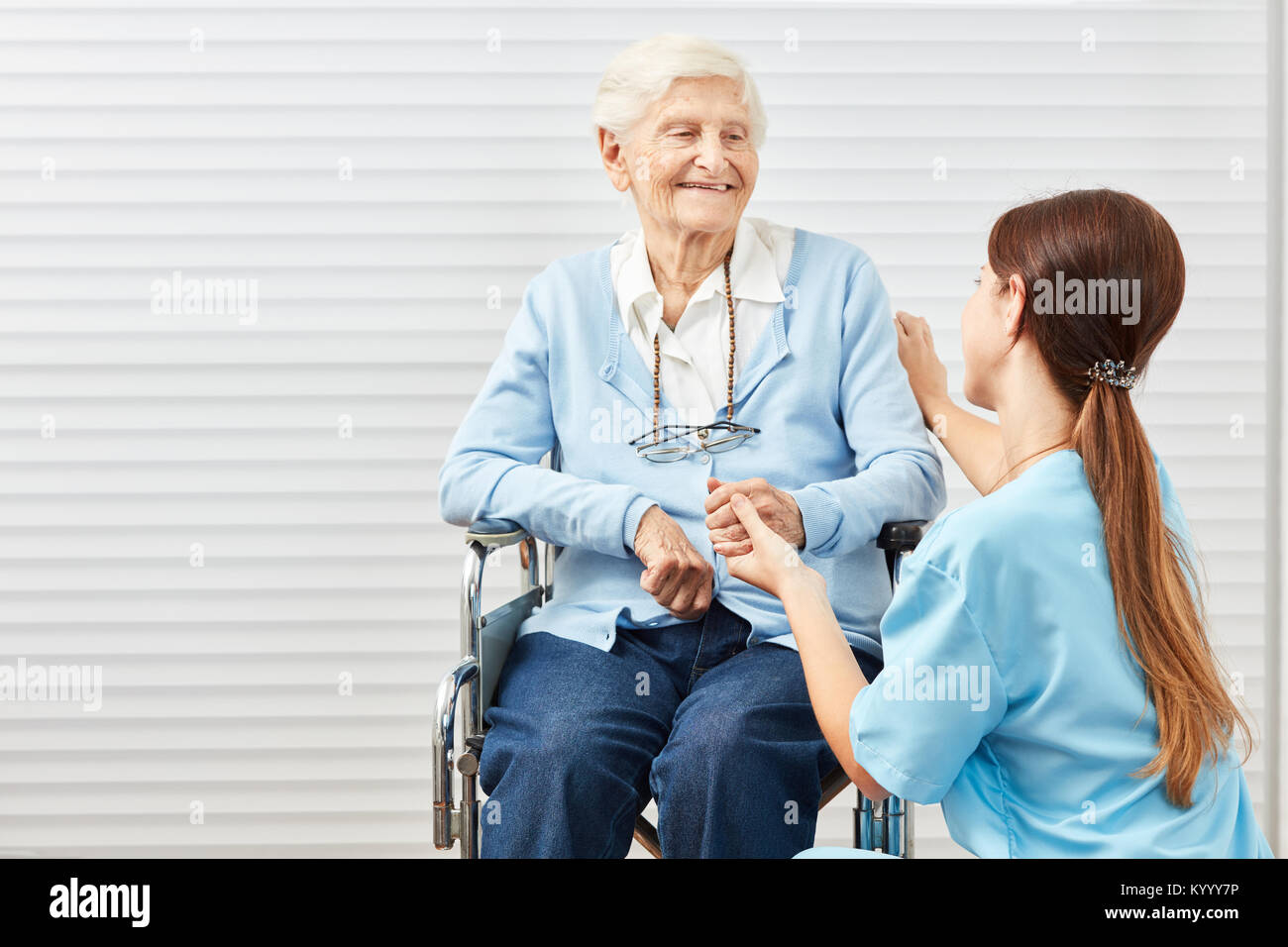 La cura della donna sulle cure infermieristiche mentre cura un anziano in una sedia a rotelle Foto Stock