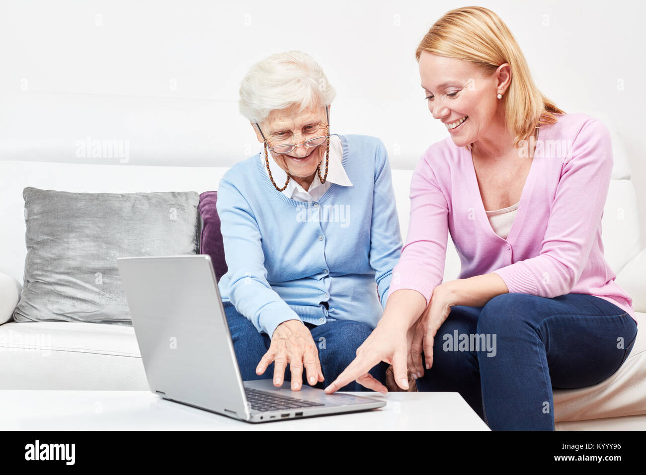 Junge Frau erklärt einer Seniorin einen Laptop Computer und das Internet Foto Stock