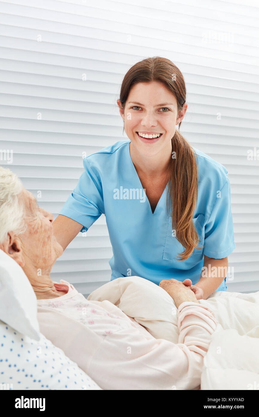 Giovane donna sorridente come un infermiere o infermiere nel campo dell'assistenza infermieristica Foto Stock