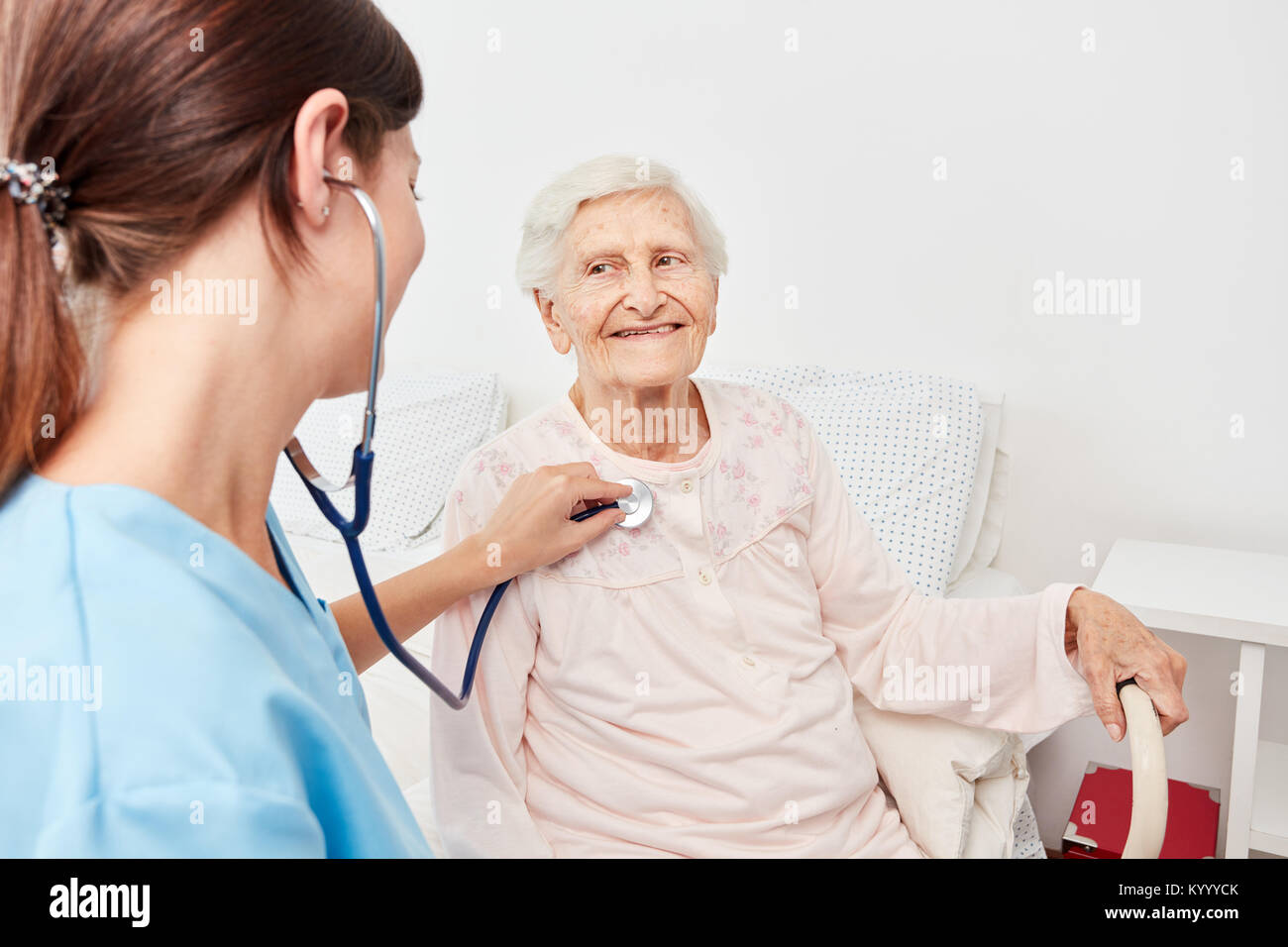 L'infermiera ascolta senior citizen con uno stetoscopio a casa Visita Foto Stock