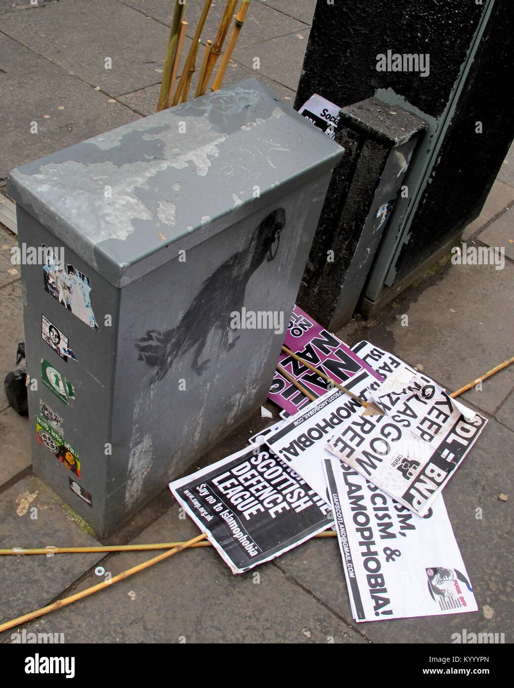 Scartato cartelloni per la dimostrazione contro la difesa scozzese League e la BNP corvo nero graffiti su strada Foto Stock