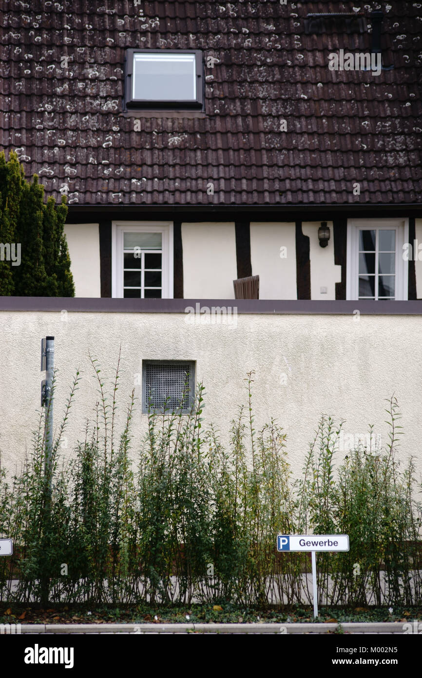 Un simbolo di parcheggio per un commerciale parcheggio nella parte anteriore di una casa in legno e muratura con una parete. Foto Stock