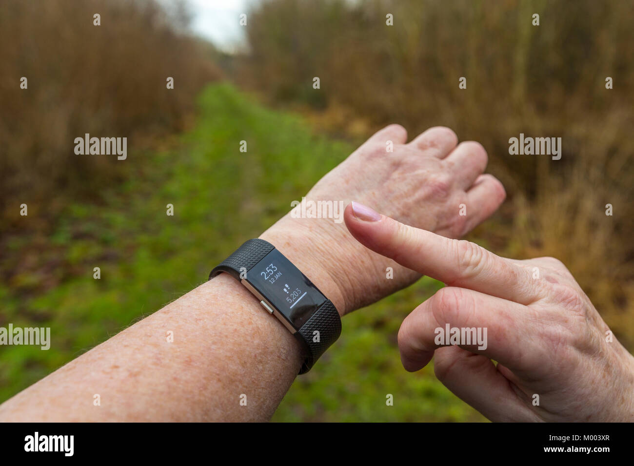 Una signora controlla i suoi passi sul suo Fitbit tracker di fitness. Foto Stock