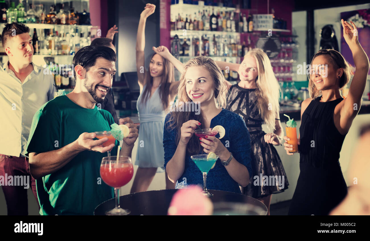 Soddisfatto maschio con femmina sono a parlare e a bere un cocktail sulla parte in club Foto Stock