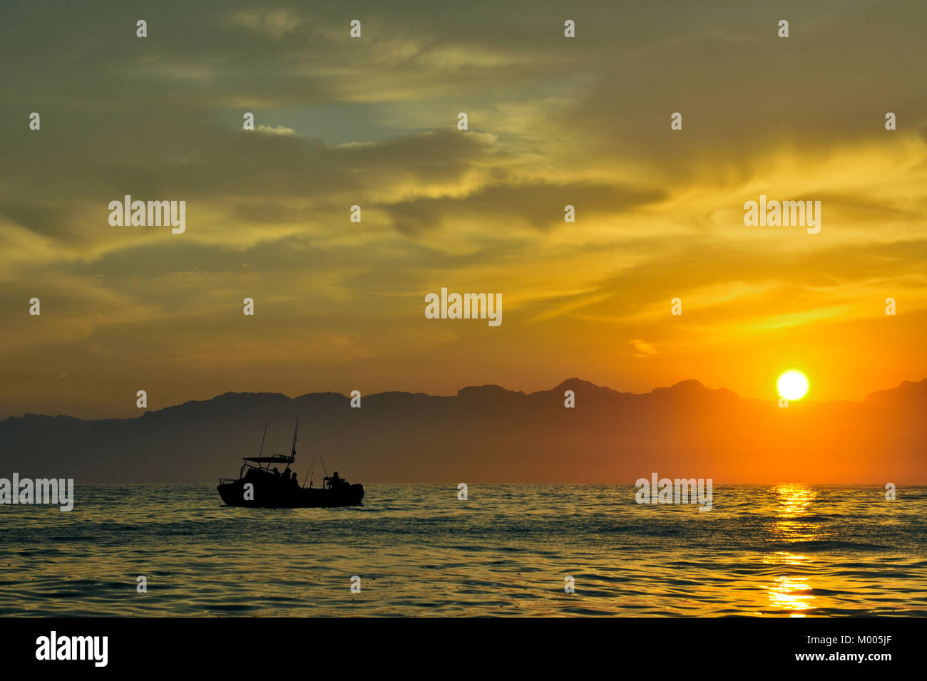 Barca da pesca silhouette in mare a sunrise. La mattina presto,l'alba,l'oceano e le montagne. Sud Africa Foto Stock