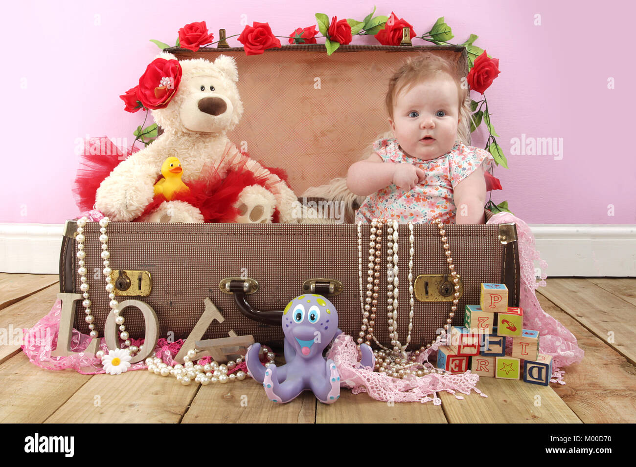 6 mese fa bella ragazza seduta con Teddy in una valigia, tempo di gioco nel vivaio Foto Stock
