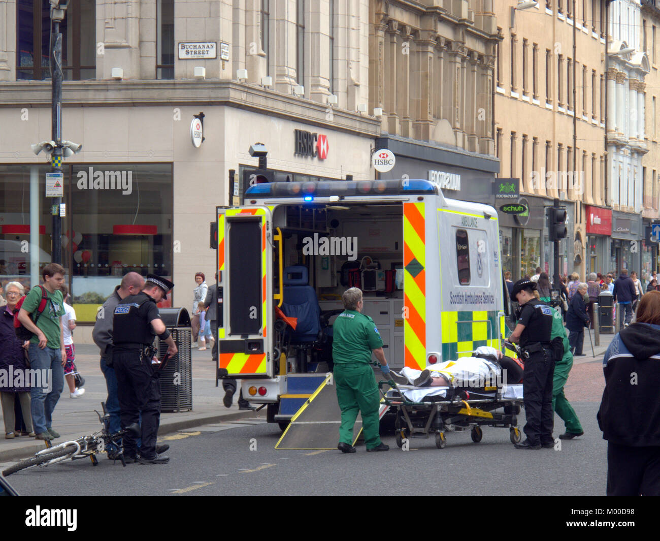 Ferito ciclista con bici Bicicletta essendo messo in retro di ambulanza con la polizia e la troupe di presenze su Argyle Street Glasgow Foto Stock