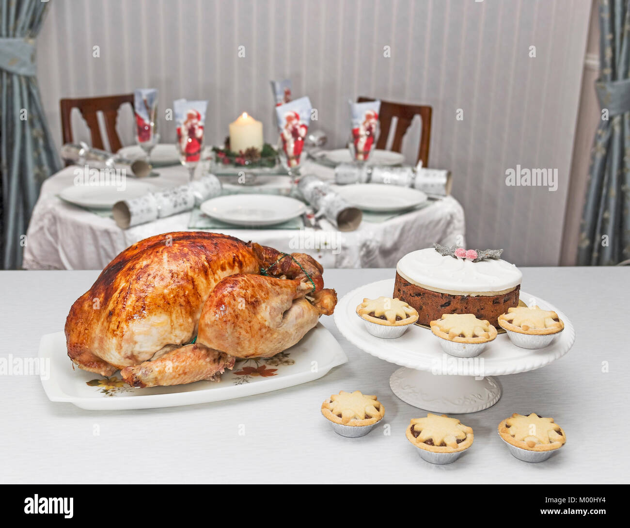 Cucina di stagione di il tacchino arrosto, pasticci di carne macinata e torta di Natale con un set tavolo da pranzo in background. Foto Stock