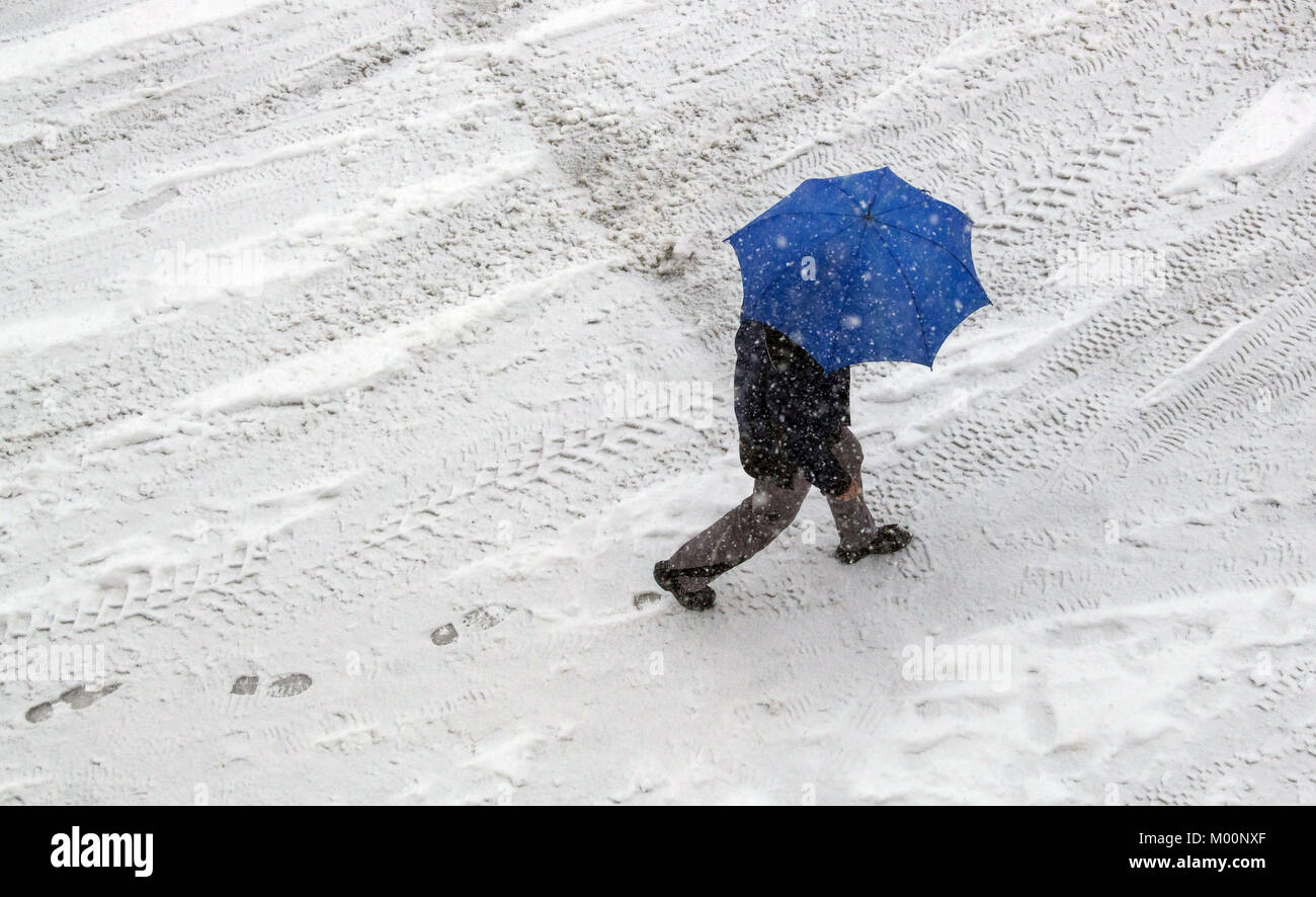Irsee, Germania. Xvii gen, 2018. Un uomo con un ombrello passeggiate lungo un ghiacciate e sentiero innevato in Irsee, Germania, 17 gennaio 2018. Credito: Pietro Kneffel/dpa/Alamy Live News Foto Stock