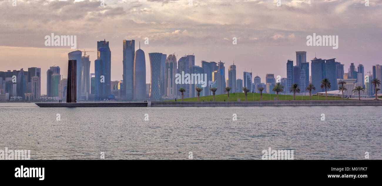 Doha, Qatar Skyline di luce diurna con golfo arabo in primo piano e grattacieli,gli alberi, le nuvole e il cielo in background Foto Stock