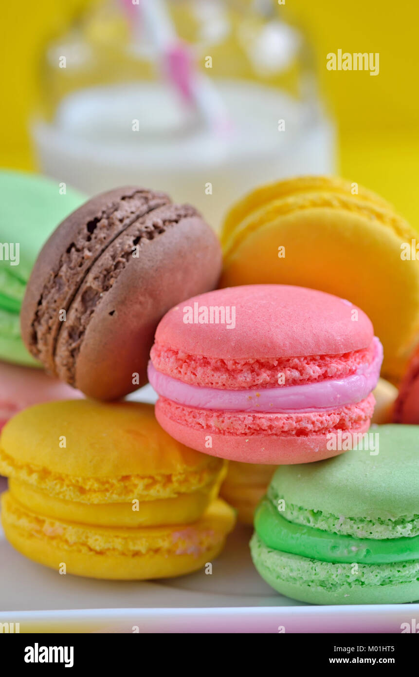 Gustosi amaretti colorati sulla piastra e latte Foto Stock