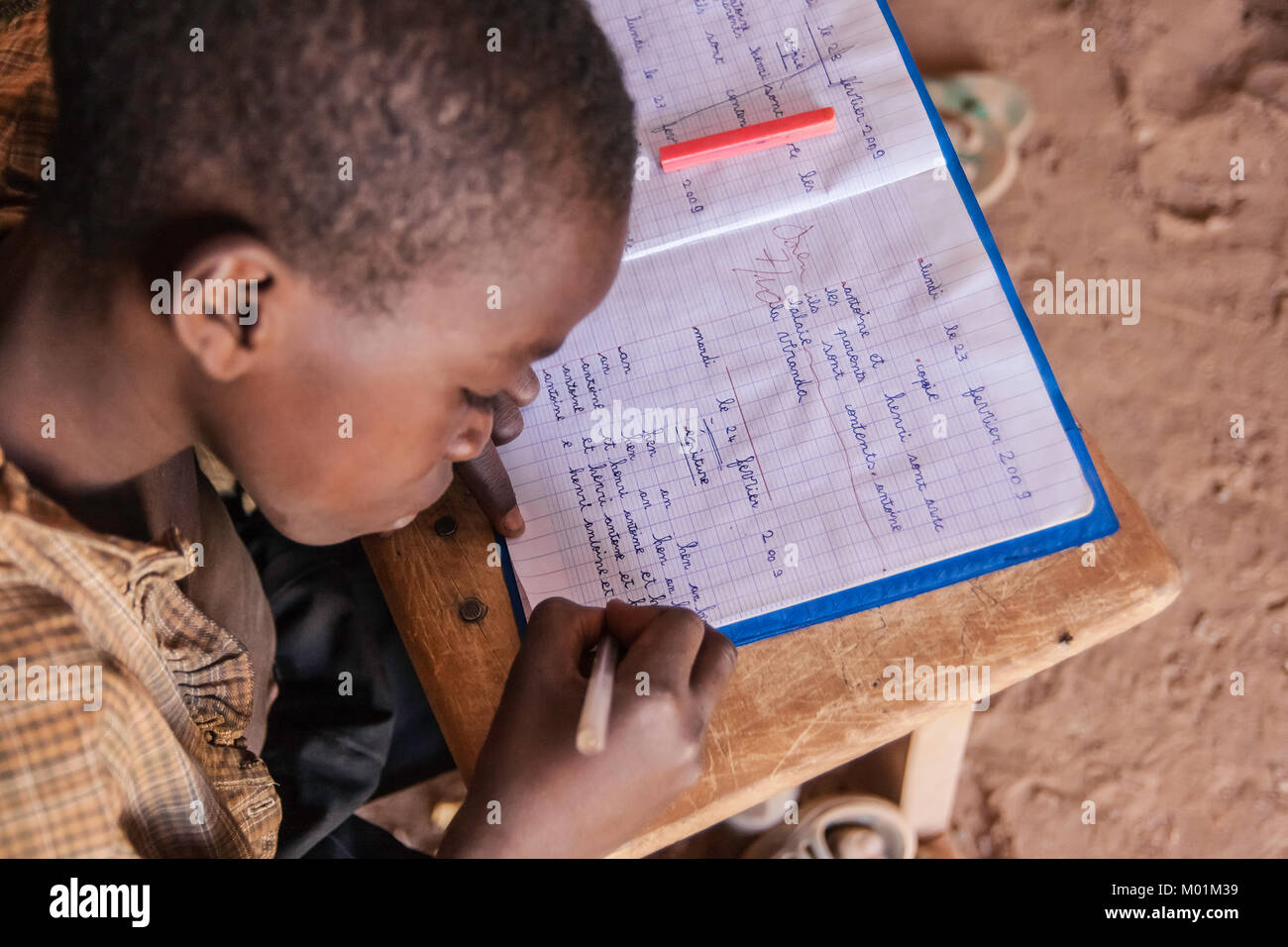 Un africano schoolkid iscritto nella sua cartella di lavoro mentre è in corso una lezione, Ouagdougou, Burkina Faso. Foto Stock