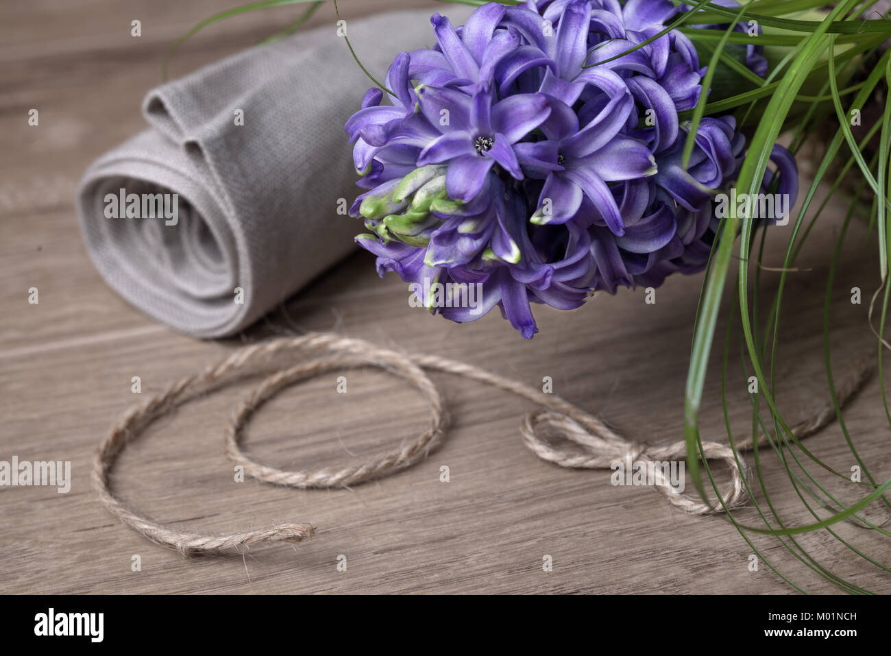 Fragranti viola giacinto, tela di lino e il cavo volteggiano su legno Foto Stock