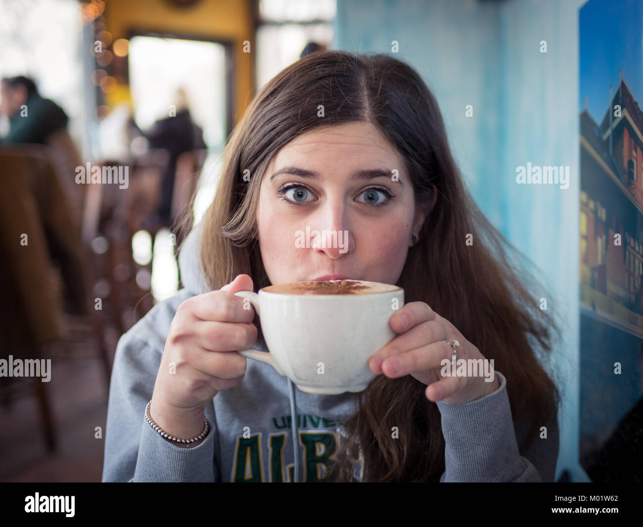 Una bella bruna ragazza sorseggia un caffè latte dal d'Lish da Tish Cafe di Saskatoon, Saskatchewan, Canada. Foto Stock