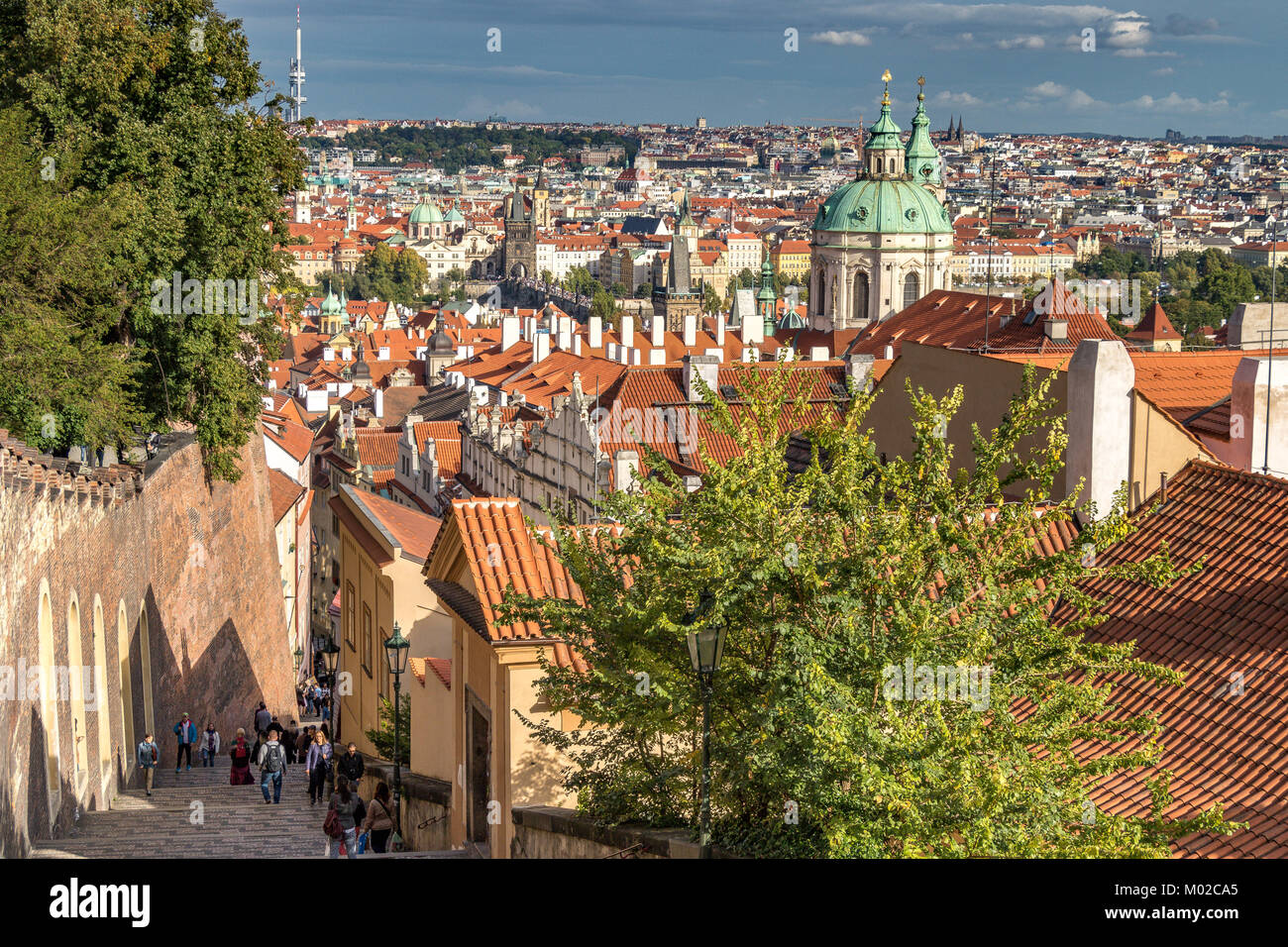 Turisti e visitatori che salgono i ripidi gradini che conducono verso il castello di Praga da Lesser Town, con la città vecchia di Praga in lontananza, Praga Foto Stock