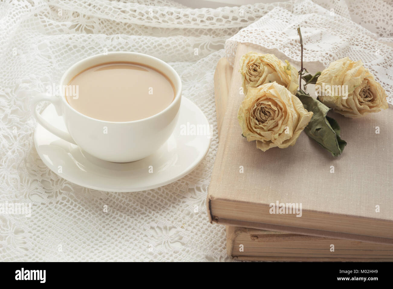 Tazza di caffè con il latte sul davanzale e prenota a secco con rose come decor sul Pizzo. Vintage. Foto Stock
