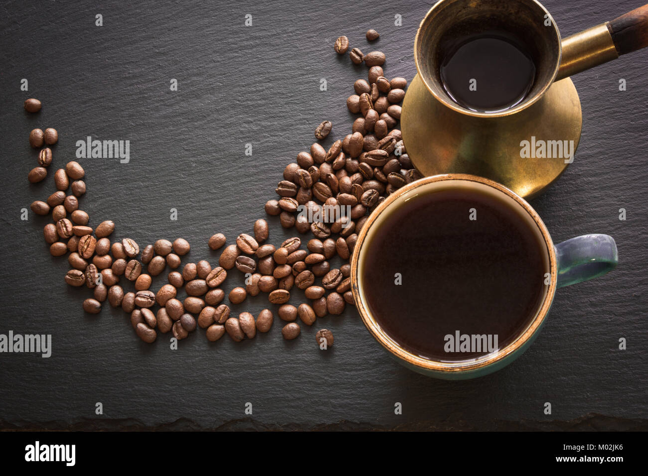 Nero caffè in rame antico cezve e cup e i chicchi di caffè sul nero ardesia con copia spazio. Foto Stock