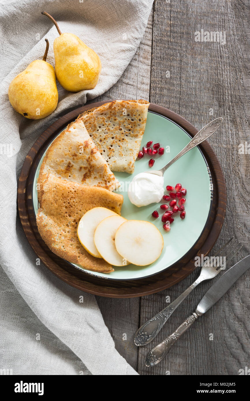 Gustosi piatti tradizionali russo prima colazione di pancake con crema di latte e frutta sulla piastra. Stile rustico. Spazio per il testo. Foto Stock