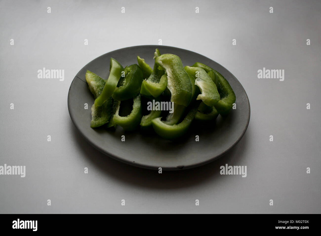 Affettato verde peperoncino poblano isolato grigio sulla piastra di calcestruzzo Foto Stock