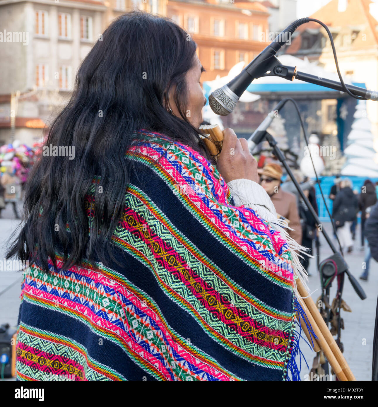 Peruviano musicista di strada esegue musica latina. L'uomo svolge un tradizionale strumento folk e indossa il tradizionale poncho colorato. Foto Stock