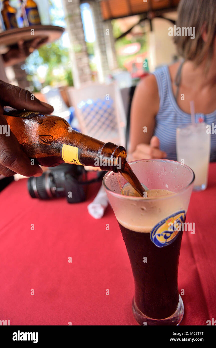 Cameriere versando una bottiglia dei Caraibi di Guinness, Grenada e Grenadine, dei Caraibi Foto Stock