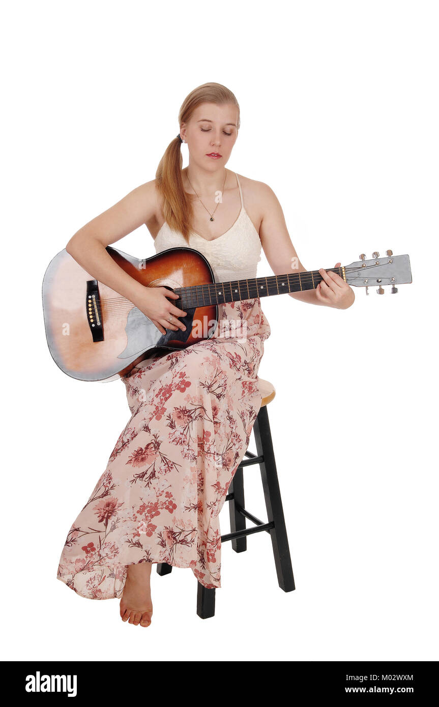 Una bellissima donna bionda in una lunga veste seduta su una poltrona con  la sua chitarra e la riproduzione, isolato per sfondo bianco Foto stock -  Alamy