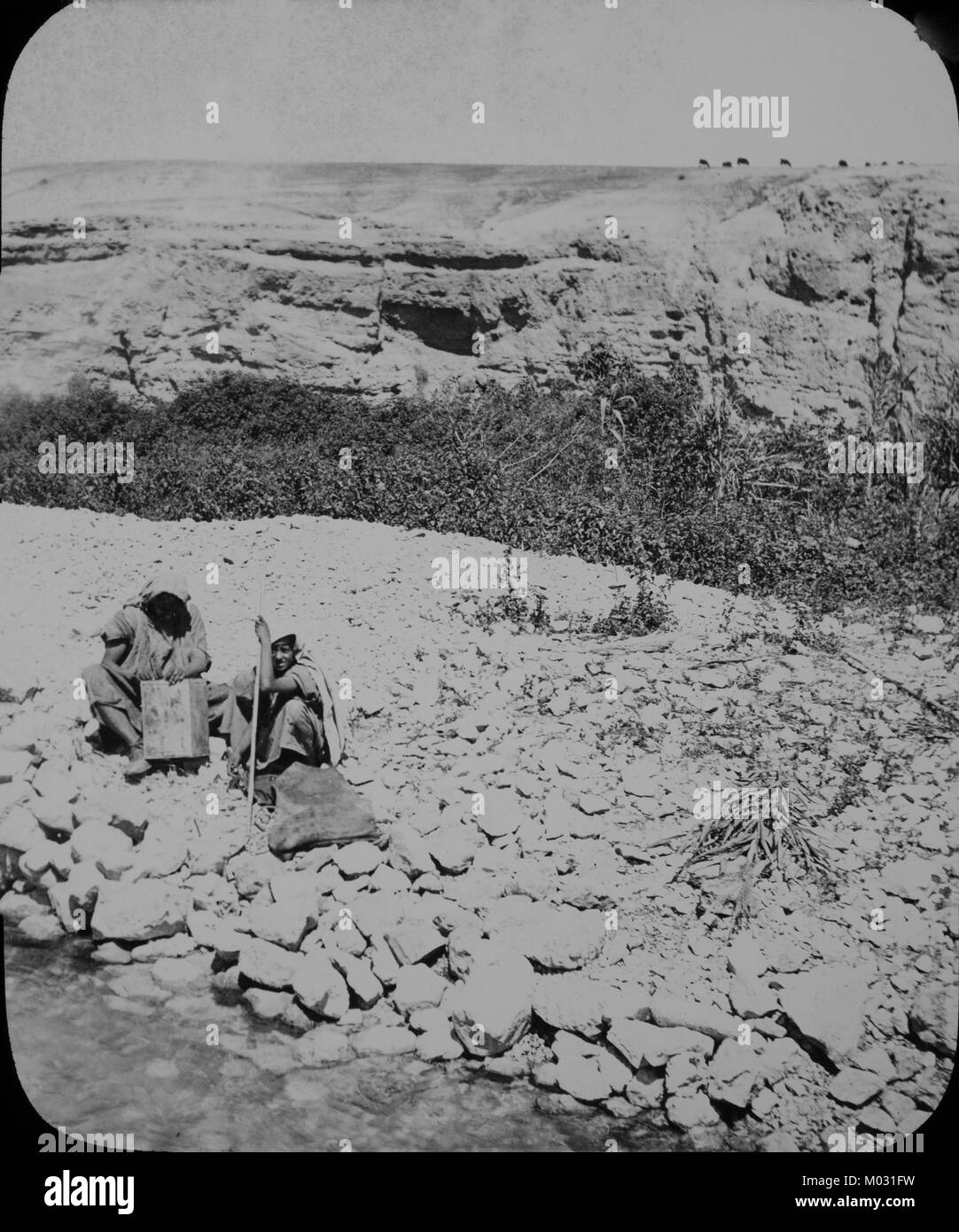 Un inizio xx secolo fotografia di due beduino seduto accanto a un fiume in Terra Santa. Foto Stock