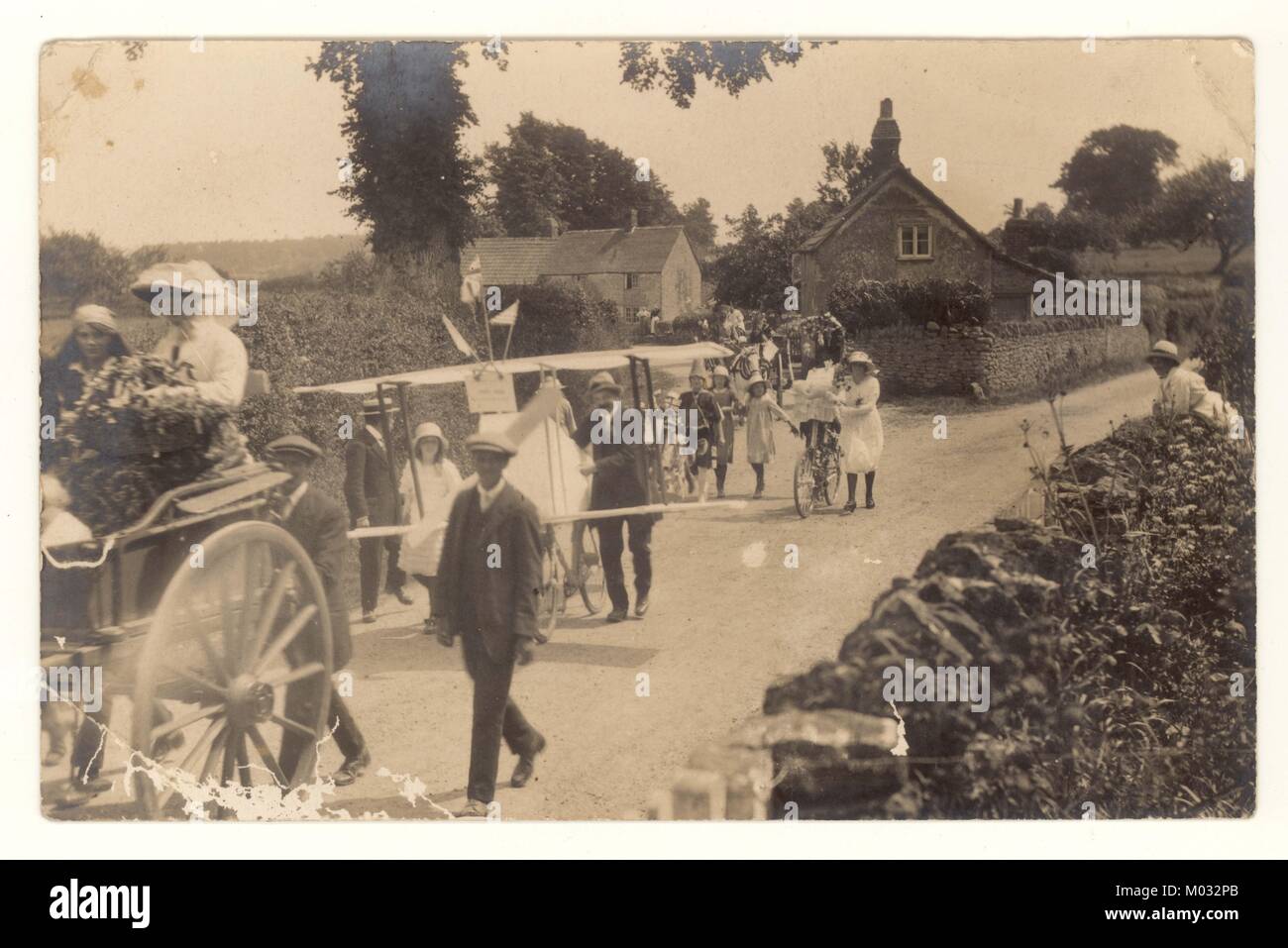 Cartolina dei primi anni '1900 di un tradizionale villaggio inglese di Stourton Caundle nella contea di Dorset. La foto mostra la parata annuale attraverso il villaggio della Friendly Society nel giorno delle mele di Quercia, il 29 maggio per commemorare il ritorno del re Carlo il trono nel 1660. le bandiere patriottiche il biplanare iniziale è una delle voci. Un'immagine iconica della vita del villaggio molto tempo fa. intorno al 1919/1920 Foto Stock