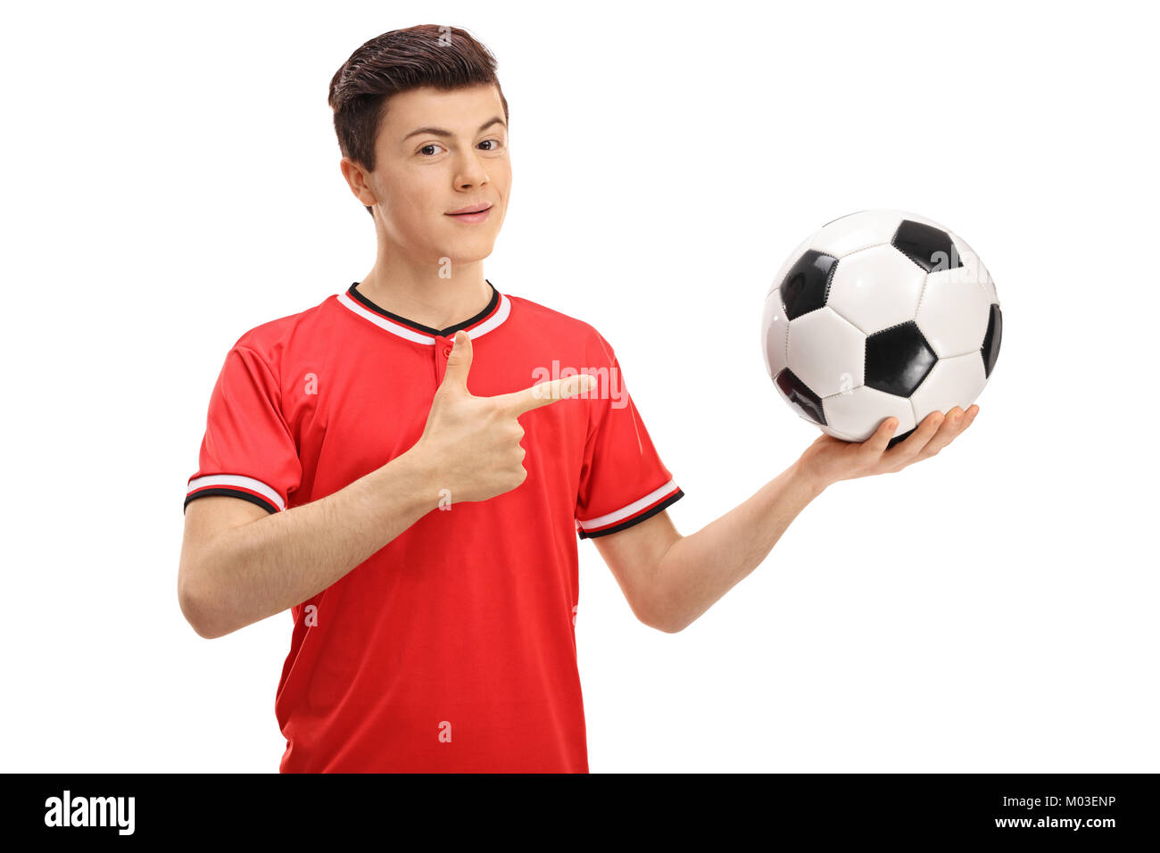 Teenage giocatore di calcio tenendo un calcio e puntamento isolati su sfondo bianco Foto Stock