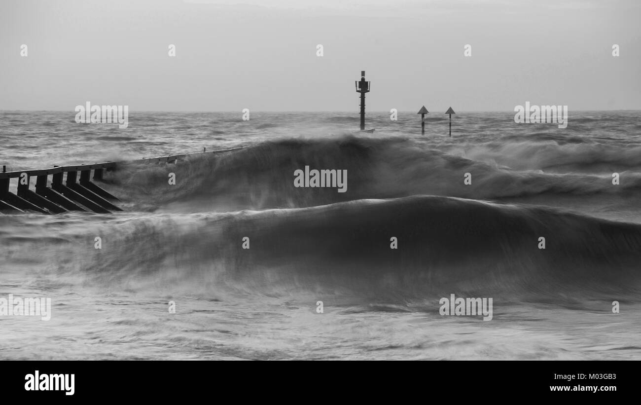 Bella moody bianco e nero paesaggio tempestoso immagine delle onde che si infrangono sulla spiaggia di sunrise Foto Stock