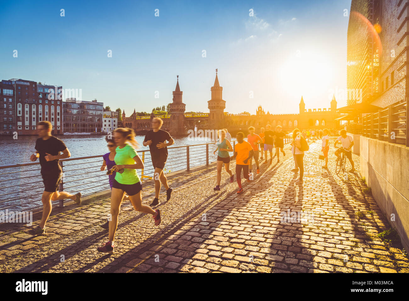 Gruppo di maschi e femmine giovani runner fuori per fare jogging in golden luce della sera al tramonto in estate con retro vintage Instagram filtro stile Foto Stock