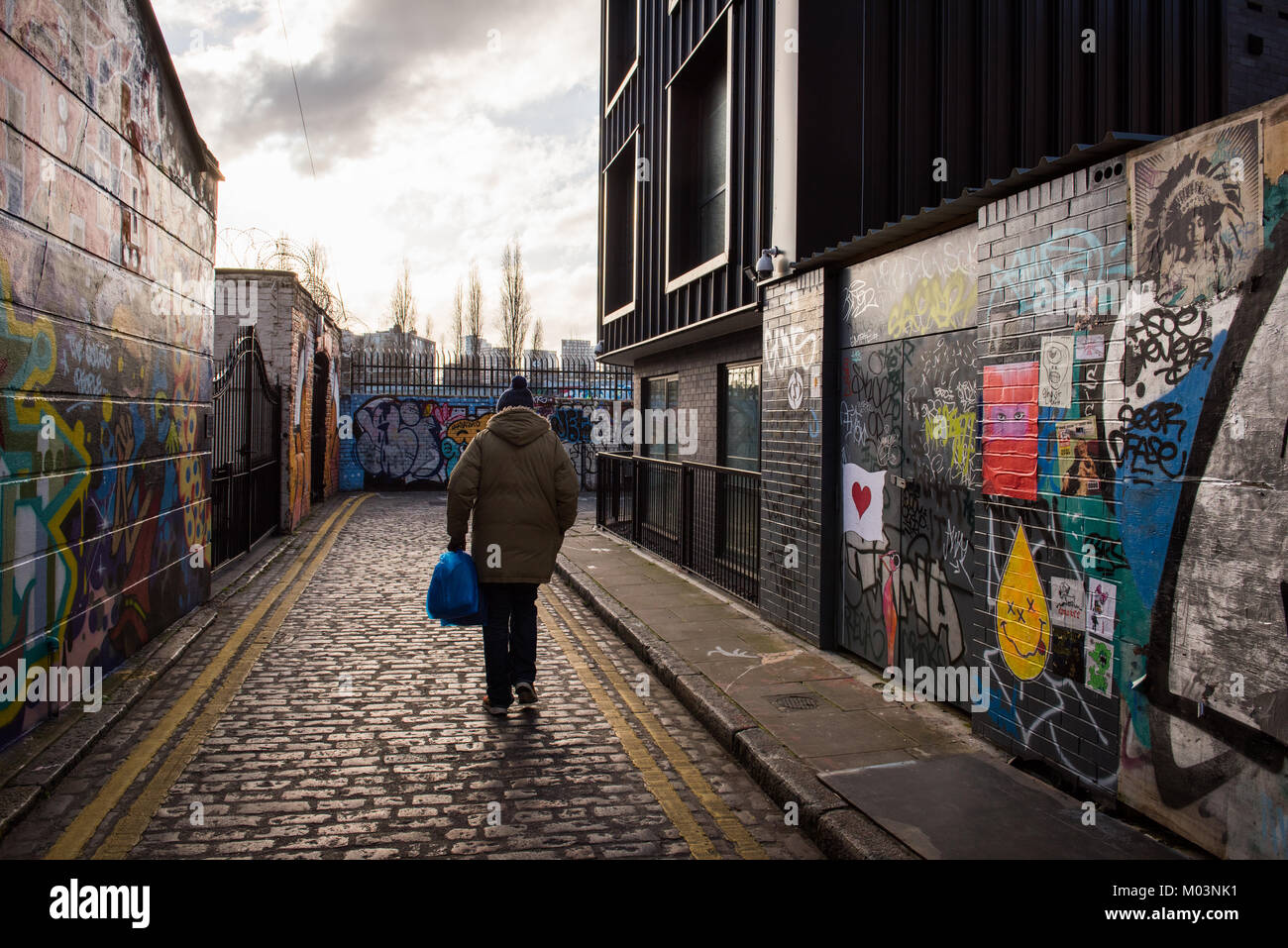 Uomo che cammina da sola lungo Grimsby Street, appena fuori la Brick Lane, East London, Regno Unito Foto Stock
