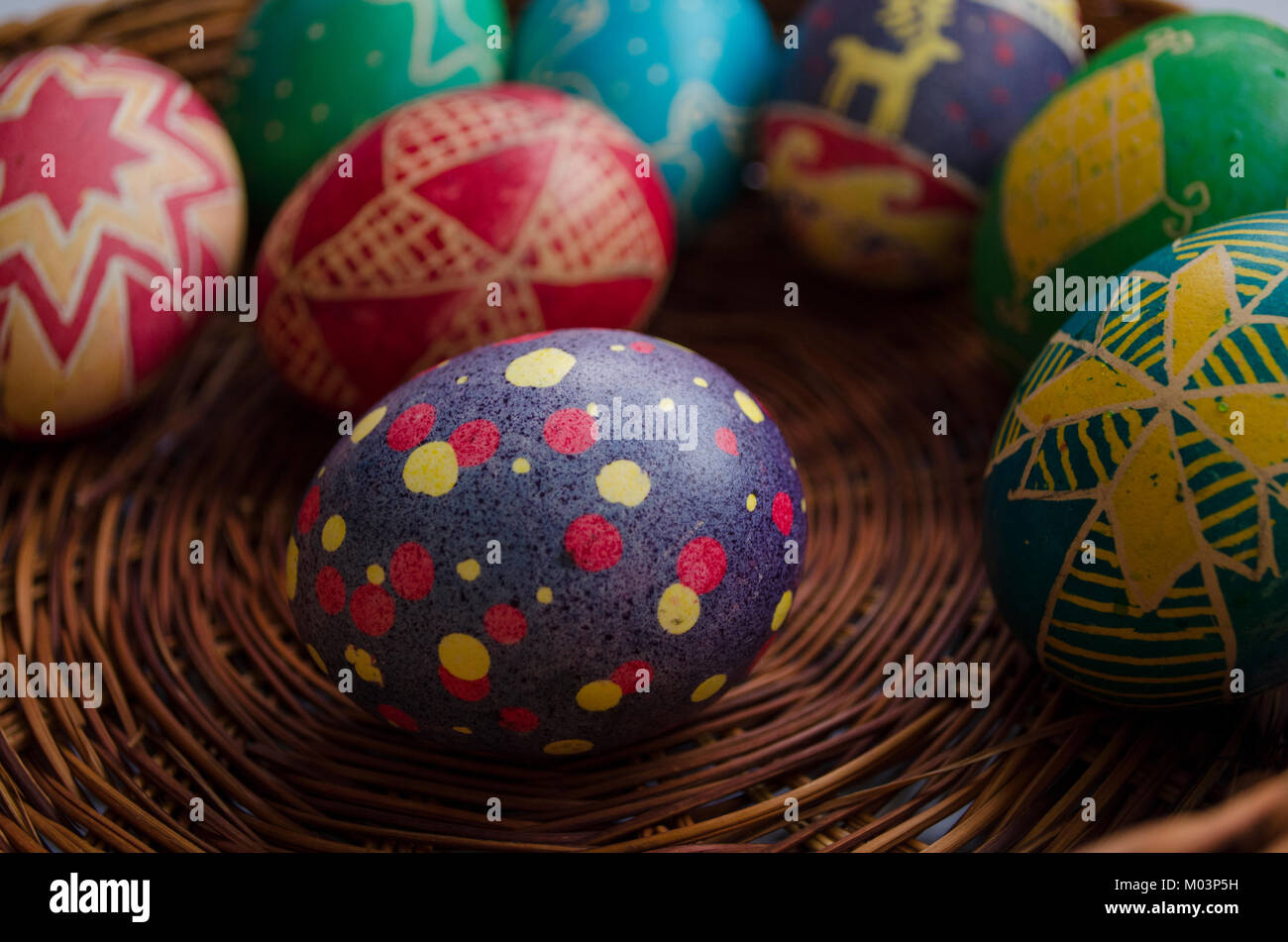 Verniciato colorato le uova di Pasqua in paglia intrecciata cestello Foto Stock