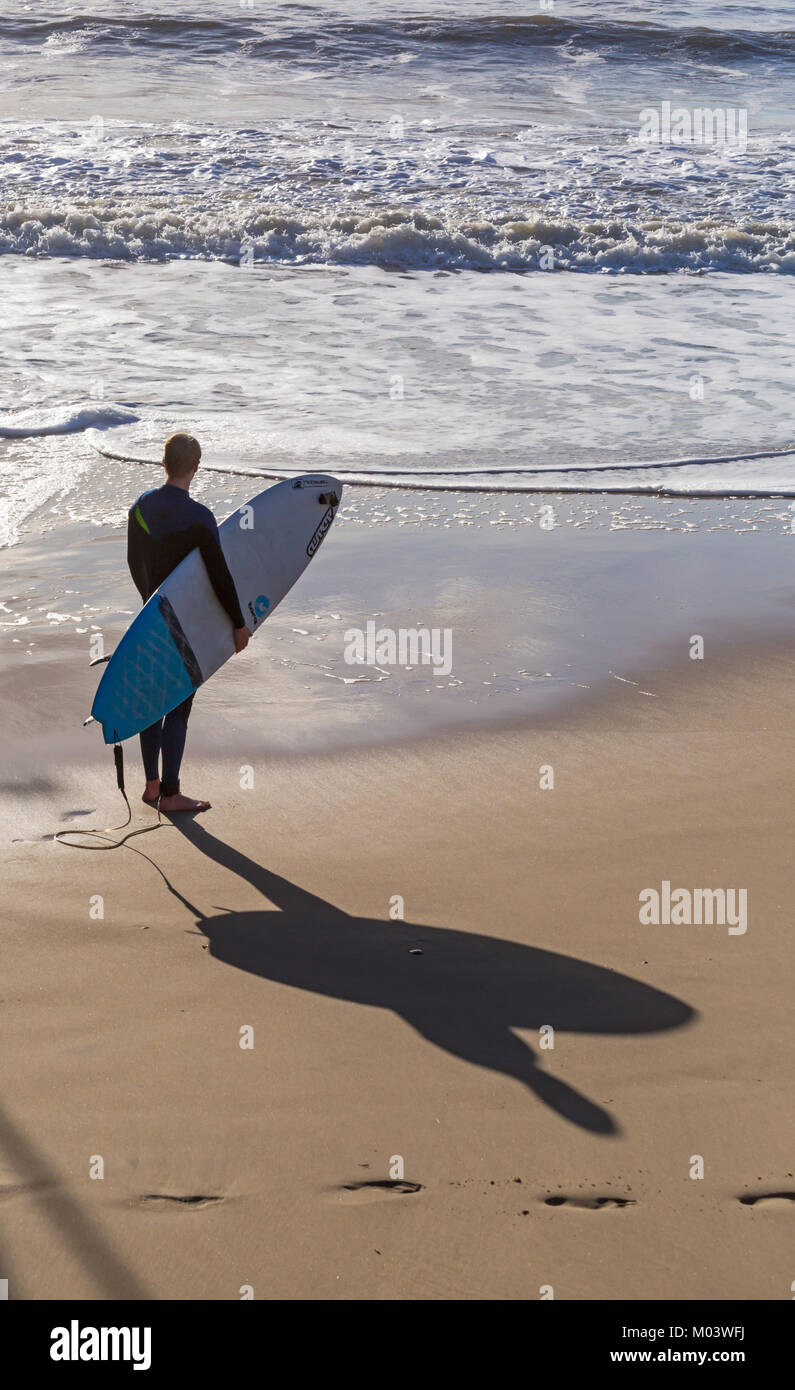 Bournemouth Dorset, Regno Unito. 18 gennaio, 2018. Regno Unito: meteo dopo una molto ventoso notte una bella giornata di sole a Bournemouth Beach. Surfer pronto per effettuare la maggior parte delle grandi onde e instabile dei mari. Surfer tenendo la scheda in piedi sul mare guardando le onde del mare con ombra sulla sabbia. Credito: Carolyn Jenkins/Alamy Live News Foto Stock