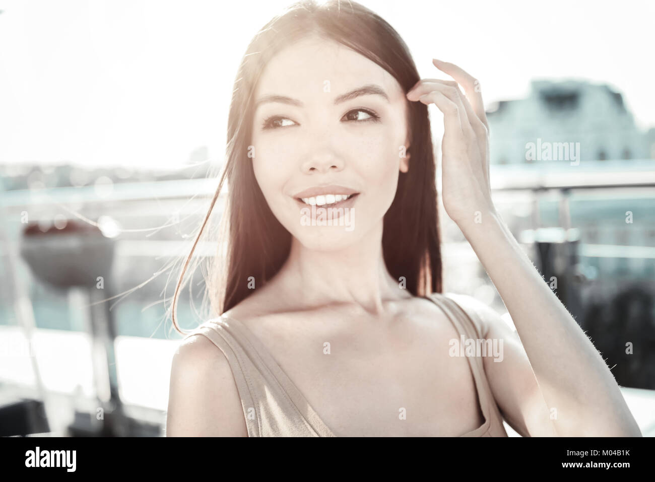 Elegante bella signora sorridente e tenendo la mano vicino alla testa. Foto Stock