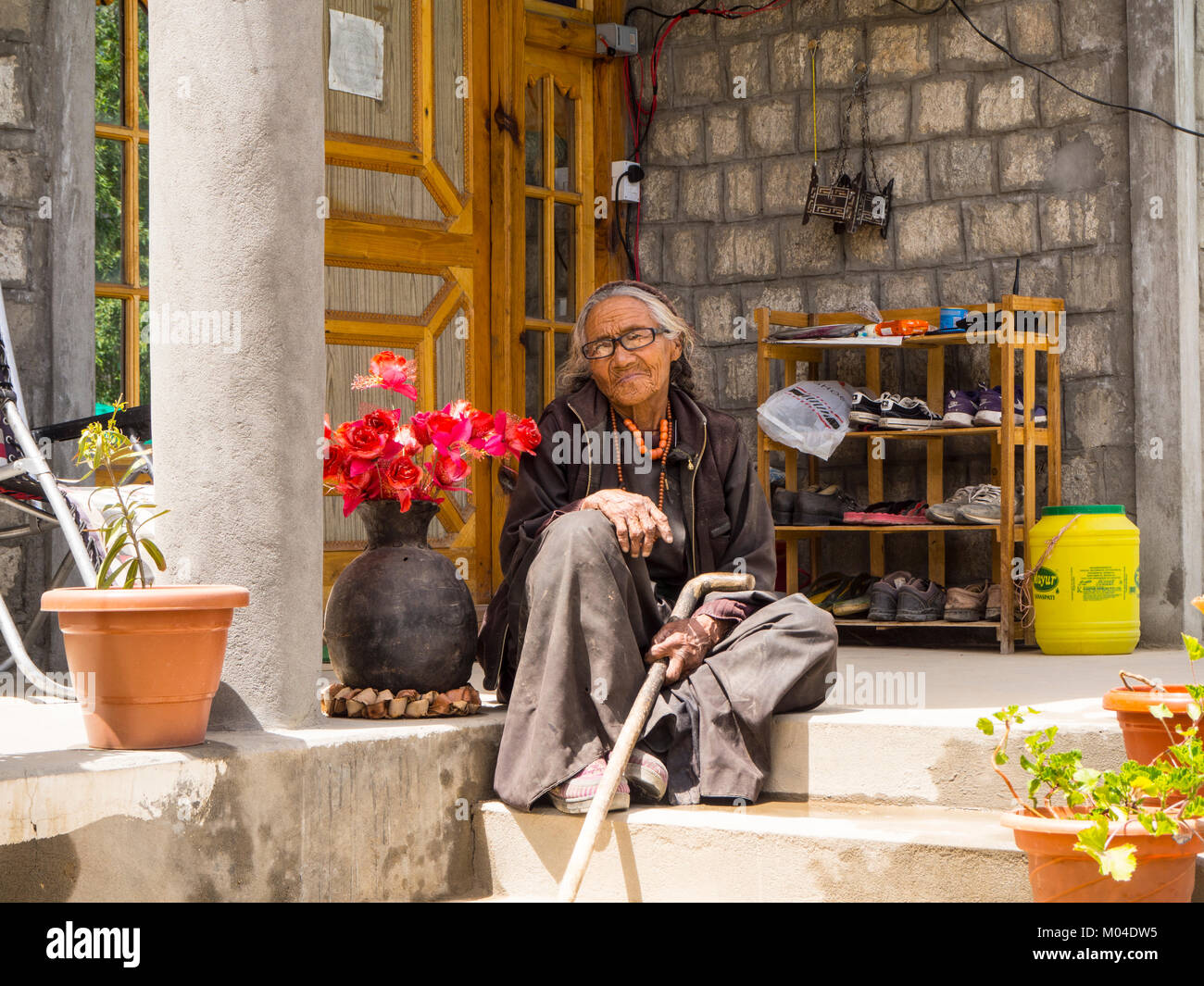 Una fotografia di una bella signora buddista in abito tradizionale sulla parte anteriore passi della sua casa Foto Stock