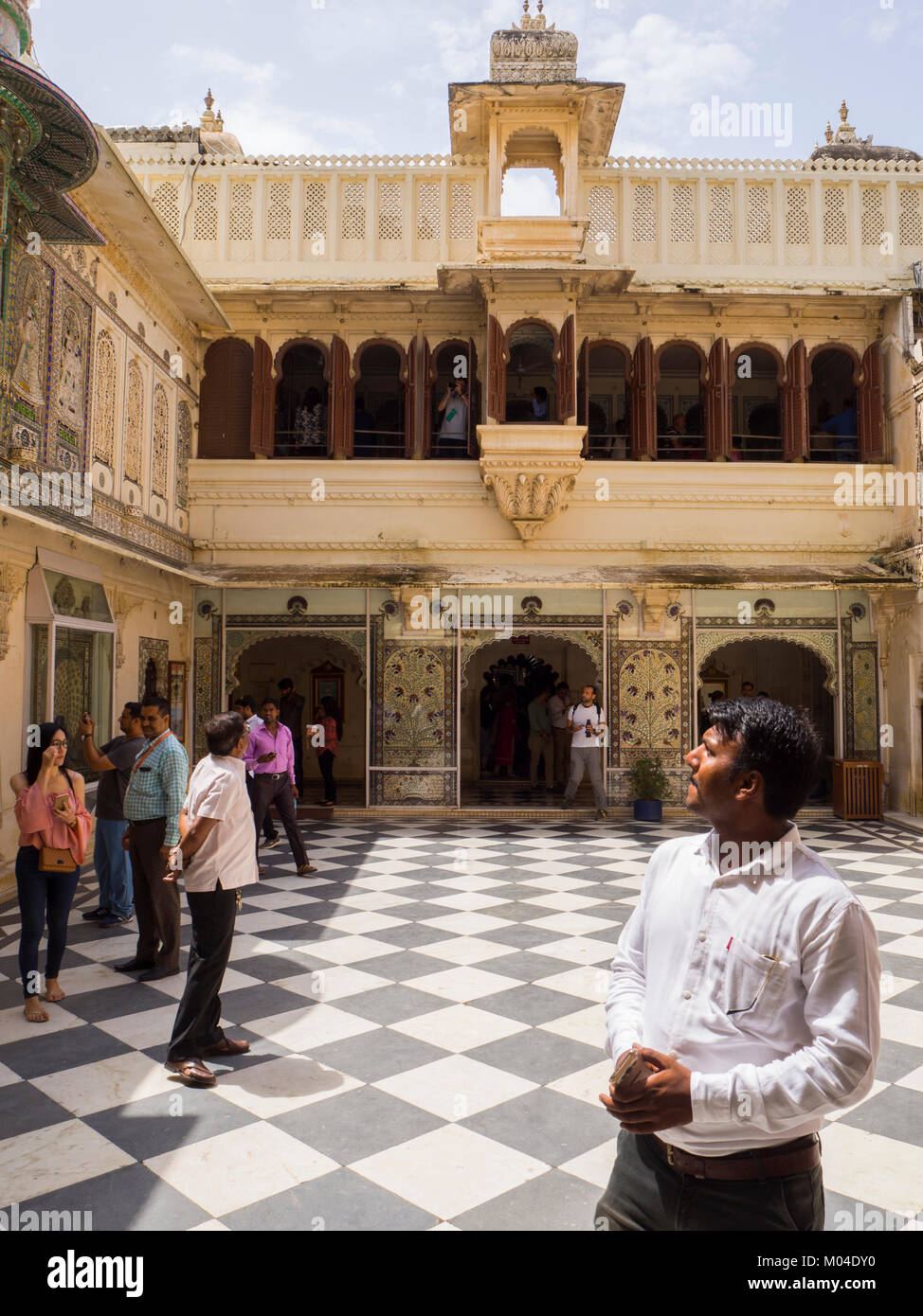 Una foto di turisti indiani nel cortile del palazzo reale di Udaipur colpito e guardando in giro Foto Stock