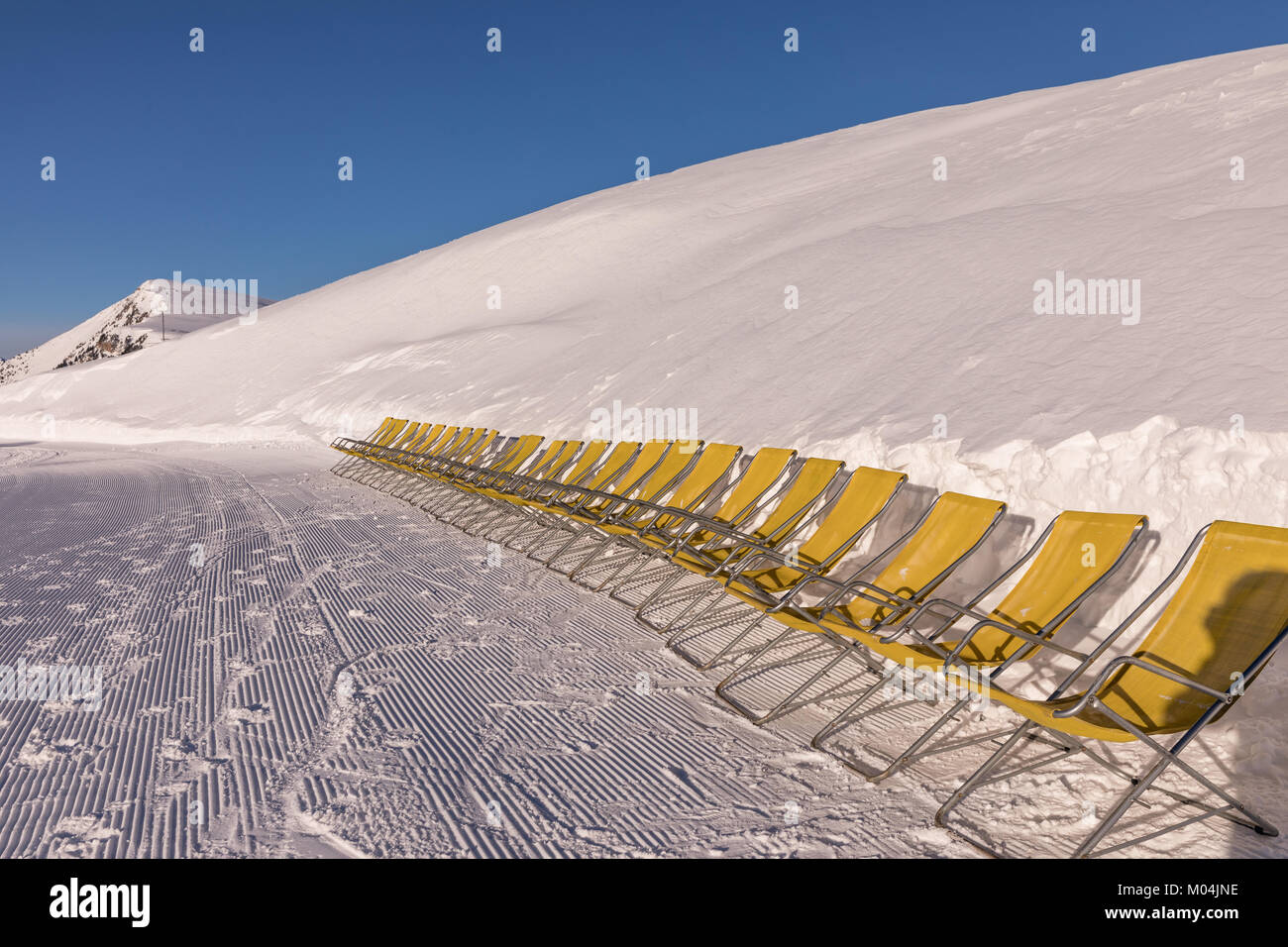 Giallo lettini per prendere il sole sul versante delle Dolomiti, sci sono.. Vuoto della pista da sci in inverno in una giornata di sole. Preparare la pista da sci. Val di Fiemme Foto Stock
