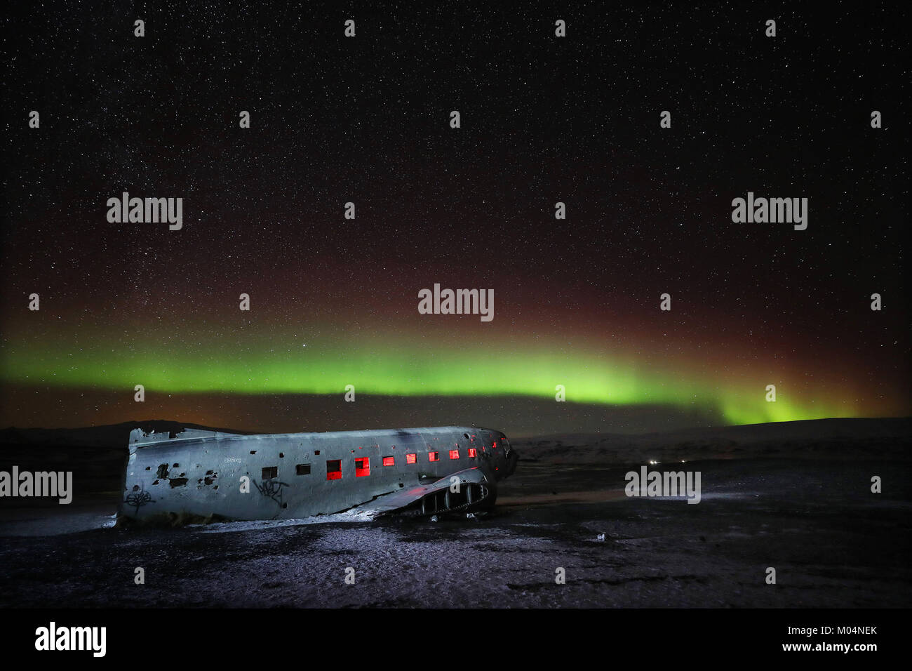 Aurora boreale, o luci del nord, brillano sopra il piano relitto di un US Navy aereo - un Super Douglas DC-3 - sulla spiaggia nera di Solheimasandur, sud dell'Islanda. Foto Stock